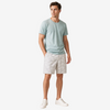 A man modeling a light sage green crewneck t-shirt and light gray patterned shorts against a plain white studio background.