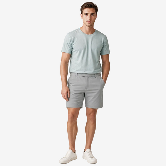 A man modeling a light sage green crewneck t-shirt and light gray shorts against a plain light gray studio background.
