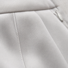 Close-up of a light gray fabric surface with stitched paneling and a small zipper pull visible on the right side.