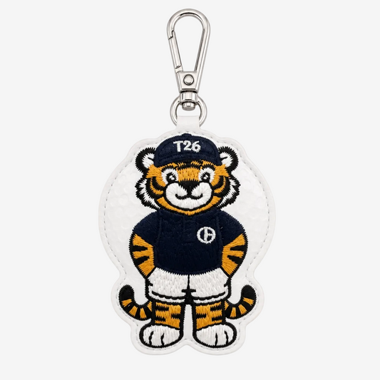 An embroidered tiger mascot keychain or bag charm on a white background. The character wears a navy blue jersey with a white 'H' logo, white shorts, and a navy cap with 'T26' in white.