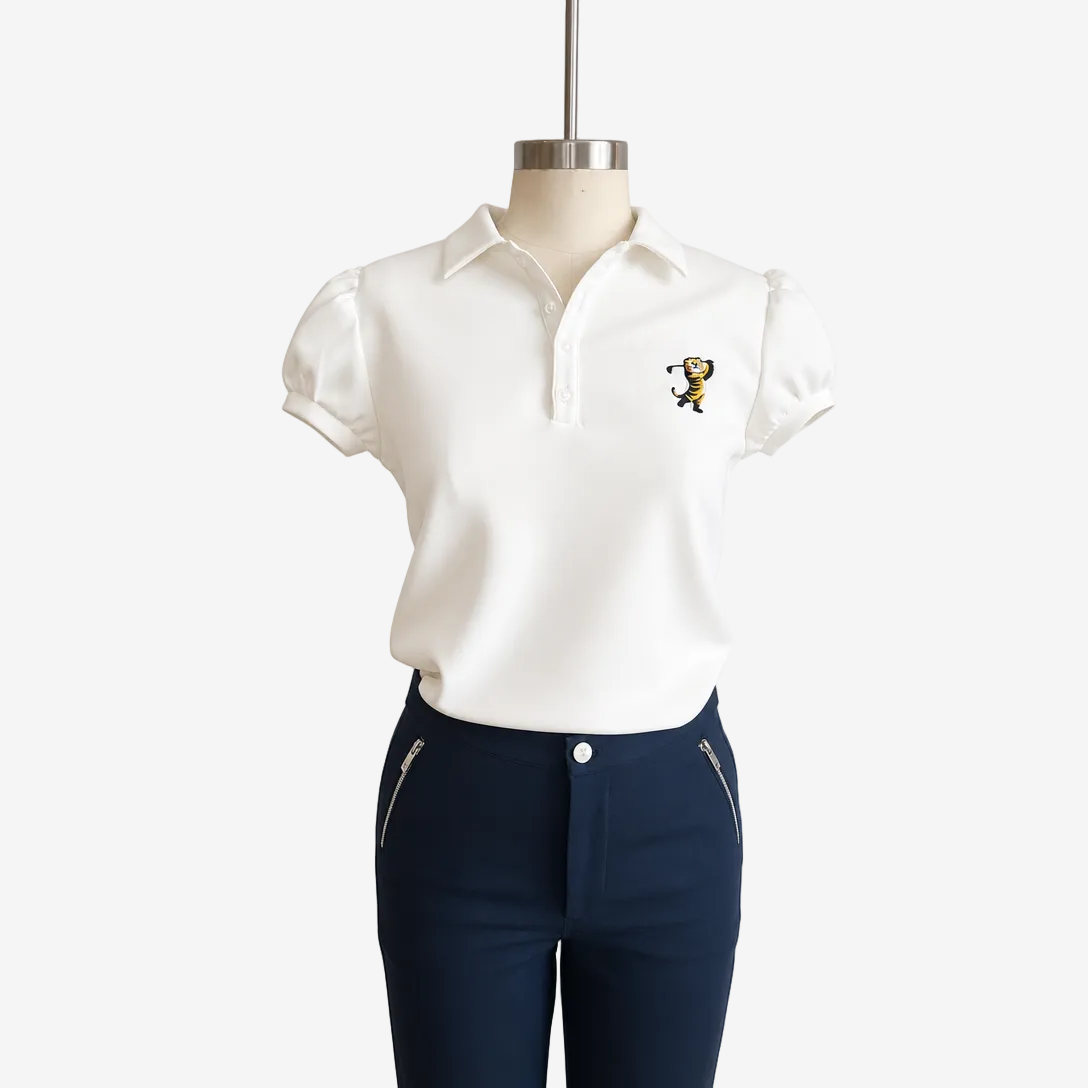 A white short-sleeve polo shirt with a small embroidered cartoon tiger on the left chest, displayed on a mannequin torso paired with navy pants against a plain white background.