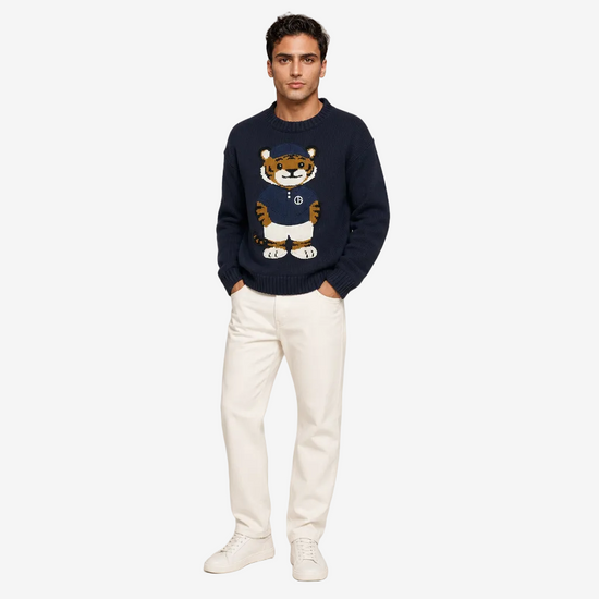 Man wearing a navy sweater with a tiger design on a plain background