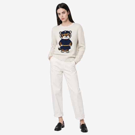 Woman wearing a cream sweater with a teddy bear design on a white background