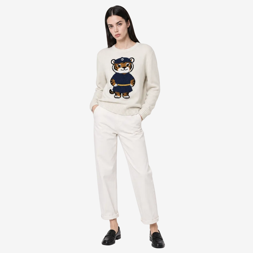 Woman wearing a cream sweater with a teddy bear design on a white background
