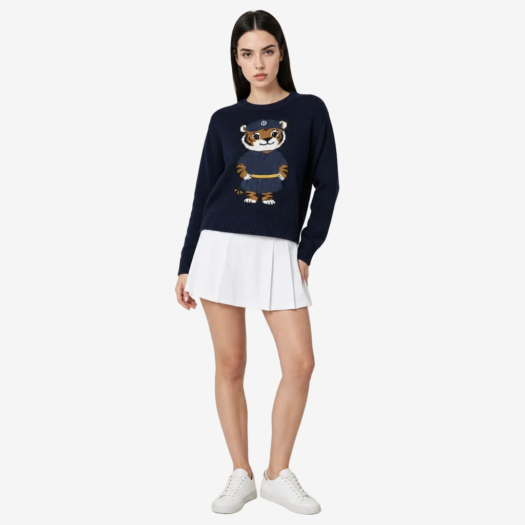 Woman wearing a navy sweater with a bear design and white skirt on a light gray background