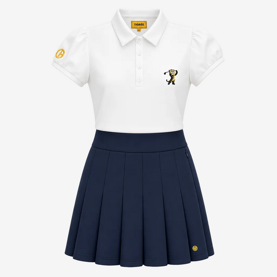 A girls' short-sleeve polo shirt and pleated skirt set. The white polo features a small embroidered mascot on the left chest and a yellow circular patch on the right sleeve, paired with a navy blue pleated skirt that has a matching yellow emblem near the hem.