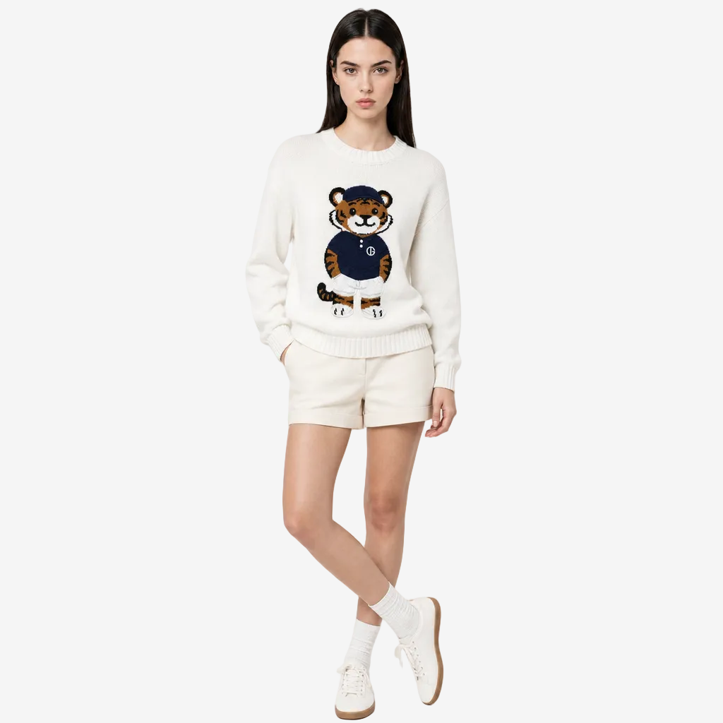 Woman wearing a white sweater with a tiger design and white shorts on a light gray background