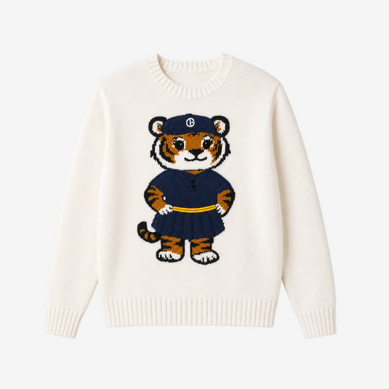 An off-white knit crewneck sweater featuring a central cartoon tiger graphic wearing a navy blue uniform with a yellow belt and a cap with a white monogram logo.