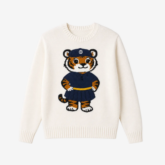 An off-white knit crewneck sweater featuring a central cartoon tiger graphic wearing a navy blue uniform with a yellow belt and a cap with a white monogram logo.
