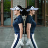 Two women in matching golf outfits standing side by side outdoors.