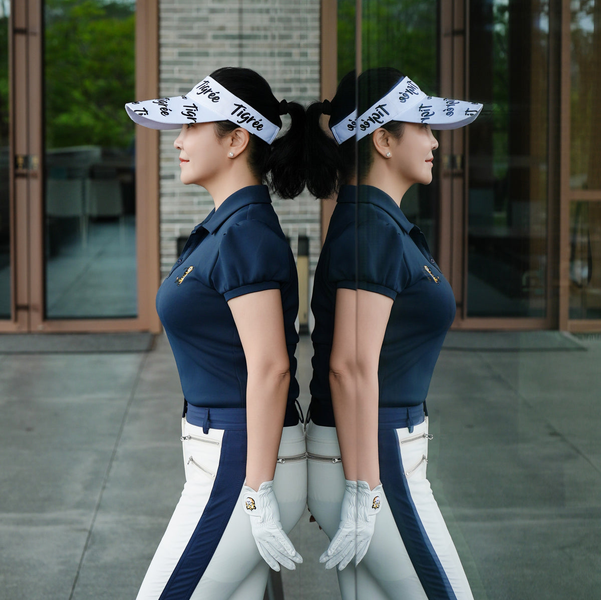 Two women in matching golf outfits standing side by side outdoors.