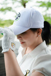 Person wearing a white cap and golf glove with a blurred green background