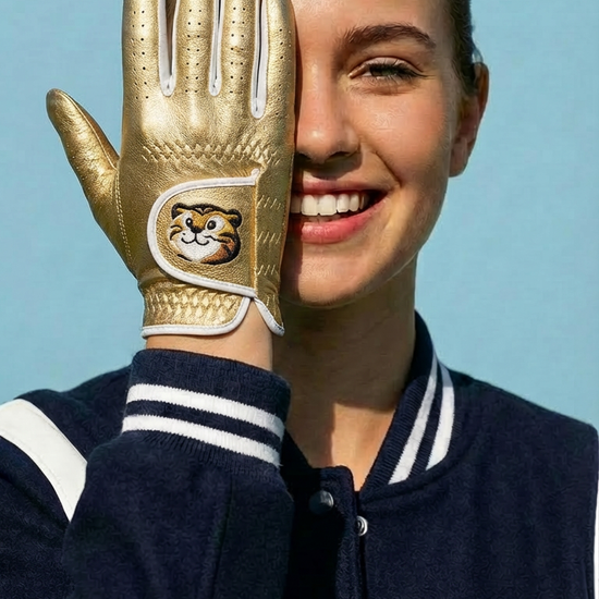 Person wearing a gold glove with a logo, smiling against a blue background