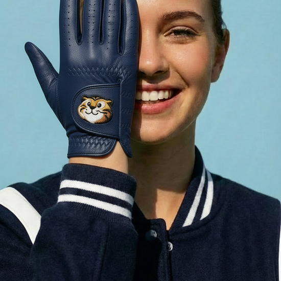 Person wearing a navy blue glove with a logo, smiling against a clear blue sky.