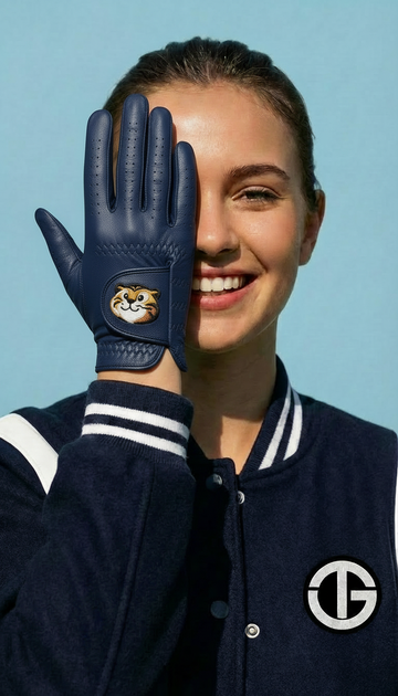 Person wearing a navy blue glove with a logo, smiling against a clear blue sky.