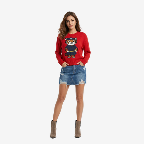 Woman wearing a red sweater with a tiger design and a denim skirt on a white background
