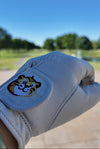 White golf glove with a tiger logo on a blurred outdoor background