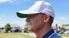 Man wearing a white cap with a logo on a golf course
