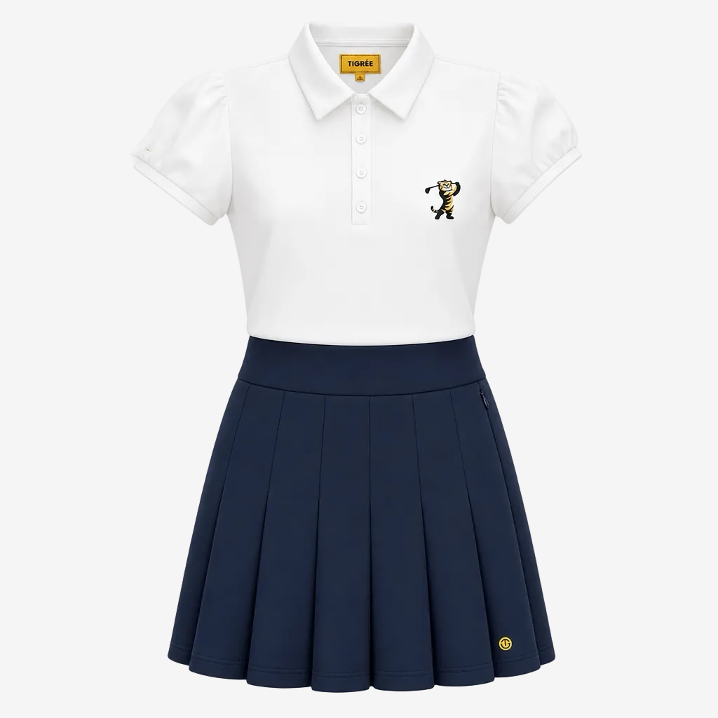 A girls' short-sleeve polo shirt and pleated skirt set from Tumbler FC. The top is white with a small embroidered Tumbler FC tiger logo on the left chest, and the skirt is navy blue with a small yellow Tumbler FC logo near the hem.
