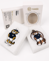 Two tiger mascot keychains displayed on white foam inserts in front of their branded packaging. The keychains feature a cartoon tiger in a navy and gold uniform, and the packaging displays the brand name 'TIGRÉE'.