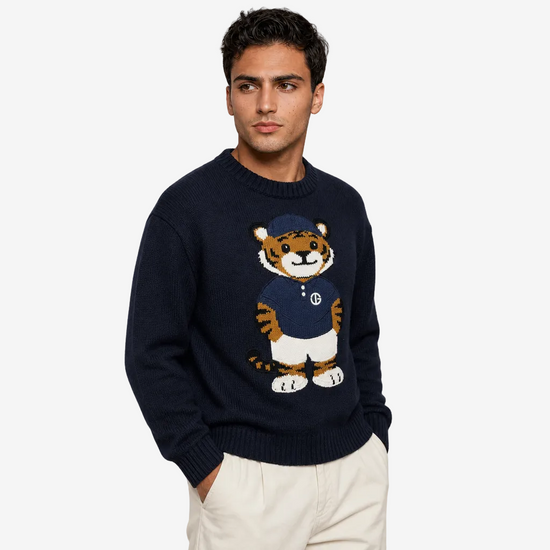 Man wearing a navy sweater with a tiger design on a plain background