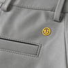 Close-up of a light gray fabric garment, likely a jacket or coat, showing a small circular yellow logo patch with a stylized 'G' on the chest.
