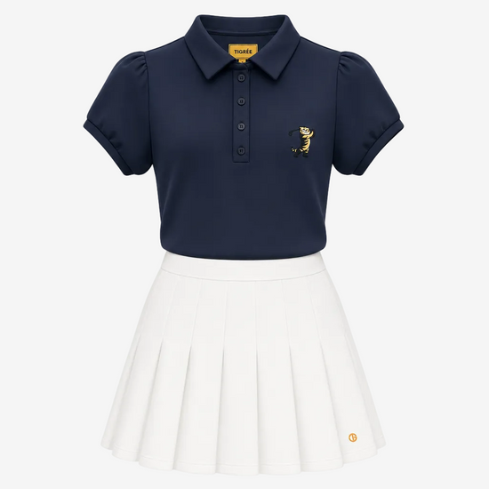 A girls' two-piece uniform set featuring a navy blue short-sleeve polo shirt with a small embroidered tiger logo on the left chest, paired with a white pleated skirt. The collar label and the skirt hem both display the 'TIGRE' brand logo.