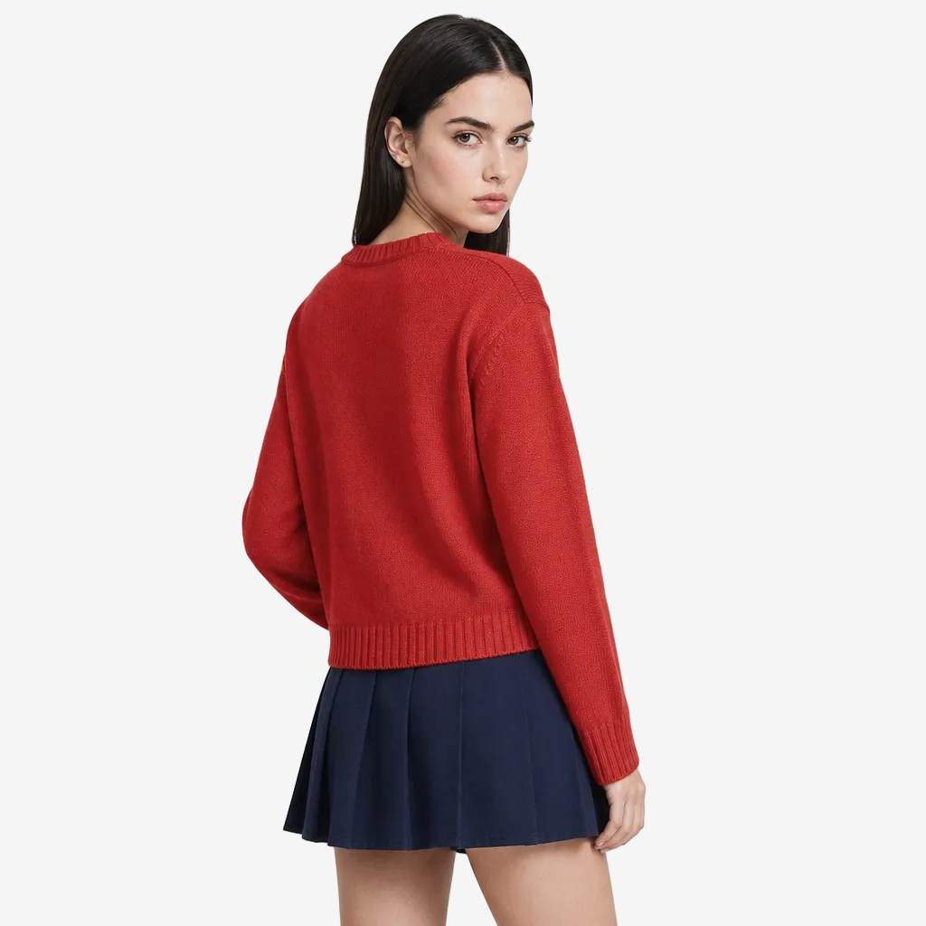 Woman wearing a red sweater and navy skirt on a light gray background