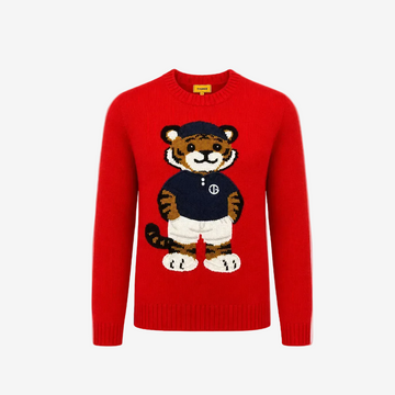 A bright red crewneck knit sweater featuring a large, detailed cartoon tiger graphic on the front. The tiger is wearing a navy blue shirt with a white 'B' logo, white shorts, and a navy blue cap.