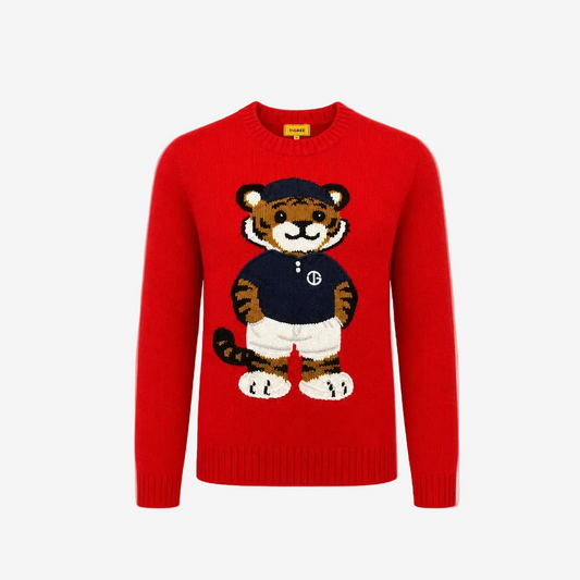 A bright red crewneck knit sweater featuring a large, detailed cartoon tiger graphic on the front. The tiger is wearing a navy blue shirt with a white 'B' logo, white shorts, and a navy blue cap.